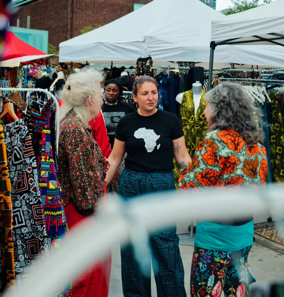 A blue mudcloth-print kimono being fastened onto a customer at a market stall
