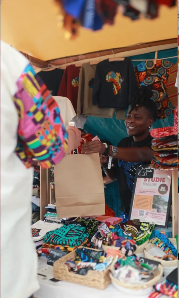 A red and orange print garment lifted from the rail at a market stall